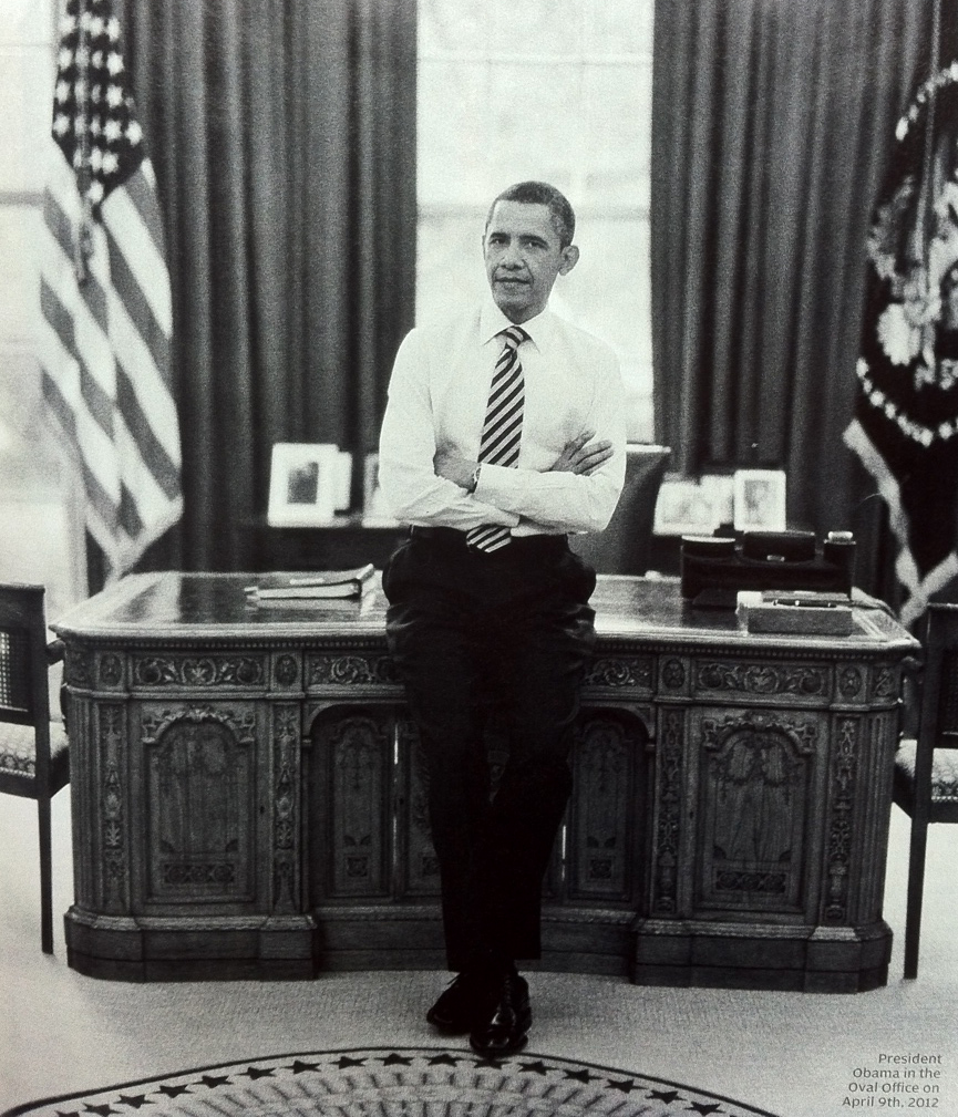President Obama leaning against the desk